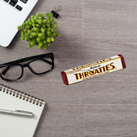 Anticol Throgsnack Throgsnies candy bar on a desk with glasses, plant, and notebook.