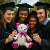 Four graduates in caps and gowns holding a teddy bear with pink accents.