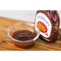 Sweet Baby Ray's barbecue sauce in a glass bowl and bottle on a wooden surface