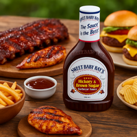 Bottle of Sweet Baby Ray's barbecue sauce with grilled chicken, fries, and burgers on a wooden table.