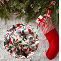 Red and white striped Christmas stocking with candy and greenery on a stone surface