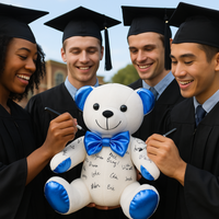 Four graduates in caps and gowns holding a teddy bear with blue accents.
