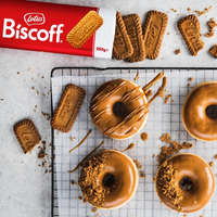 Donuts with Biscoff spread on a cooling rack with Biscoff cookies and packaging.
