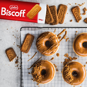 Donuts with Biscoff spread on a cooling rack with Biscoff cookies and packaging.