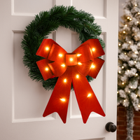 Christmas wreath with a red bow and lights on a white door
