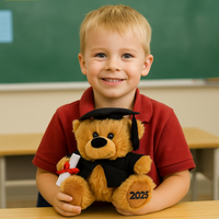 Child holding a teddy bear with a graduation cap and '2025' in a classroom setting
