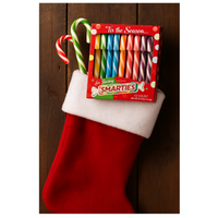 Smarties candy package with candy canes in a red stocking against a wooden background